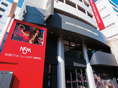 「NSM」と書かれた赤い看板と隣接する建物