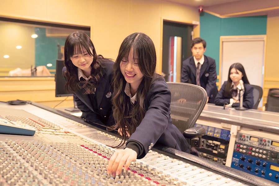 レコーディング機材のつまみを回す学生たち