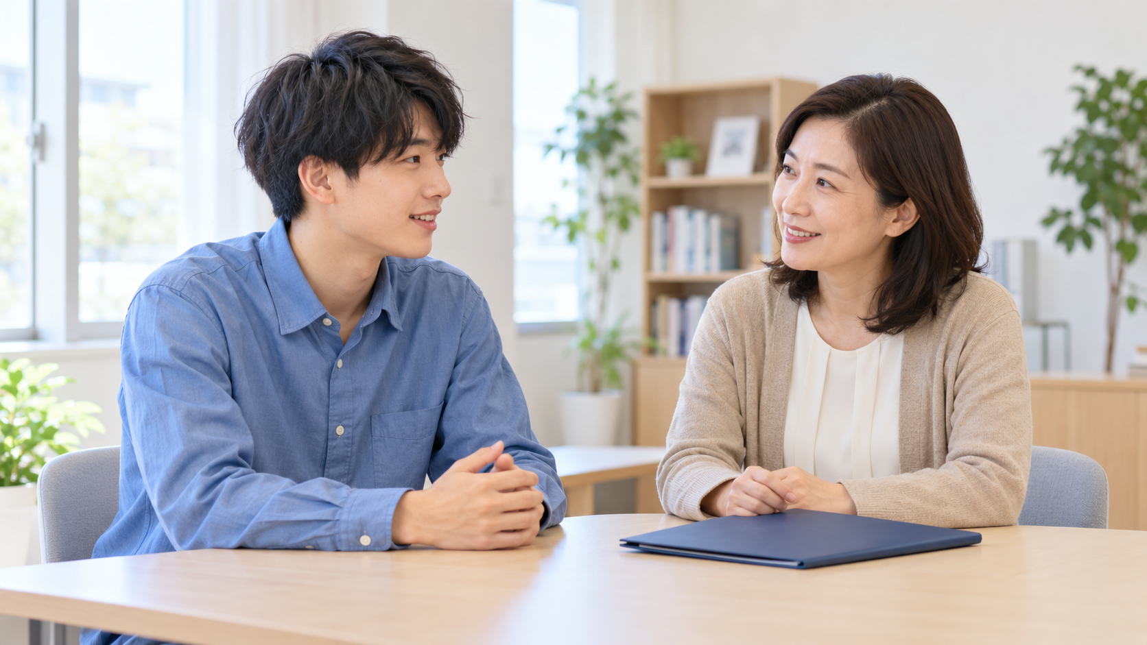 進学相談室で奨学金の準備について相談する若い男性と女性相談員のイメージ